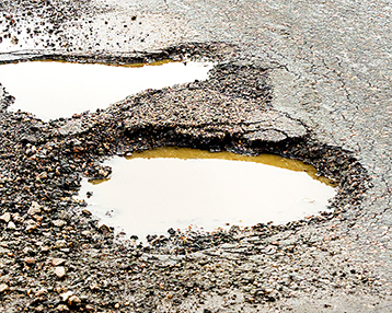 Old road. Concept highway in huge pits and potholes cloudy wea nids-de-poule